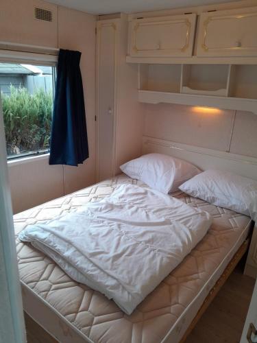 an empty bed in a room with a window at Chalet 426 met airco familiecamping de Tien Heugten Schoonloo Drenthe in Schoonloo
