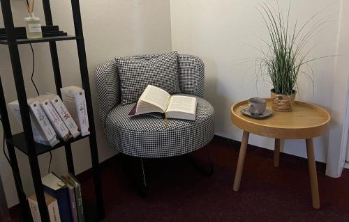 a chair with an open book and a table at Pension Kulturhaus Niederau in Niederau