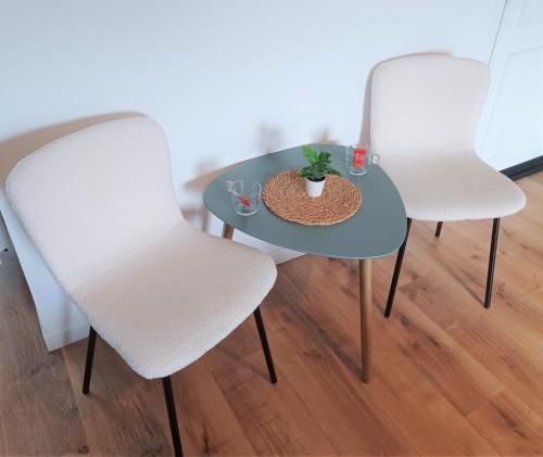 Deux chaises blanches et une table avec une plante sur la table dans l'établissement "Au pied du Beffroi" - Superbe emplacement, à Arras