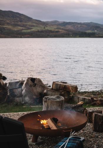 a fire pit next to a body of water at Shoreland Lodges - Cherry Lodge in Fort Augustus