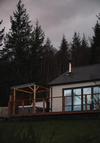 a house with a large deck and a building at Shoreland Lodges - Cherry Lodge in Fort Augustus