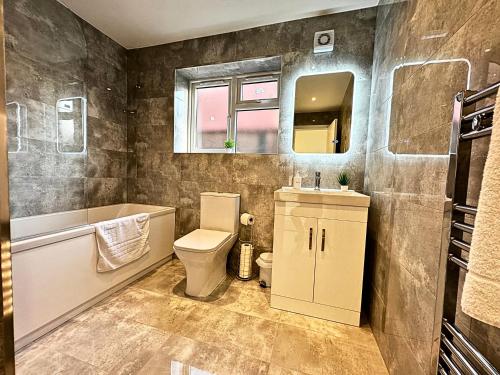a bathroom with a toilet and a sink and a mirror at Heathrow Charge and Go-FREE PARKING-Electric vehicle charging- Near Heathrow airport 5 min drive-Near Restaurants-Near Tesco Extra- Pet Friendly in Stanwell