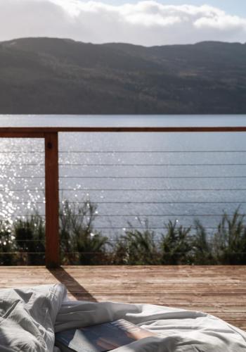 a bed on a deck with a view of the water at Shoreland Lodges - Holly Lodge in Fort Augustus