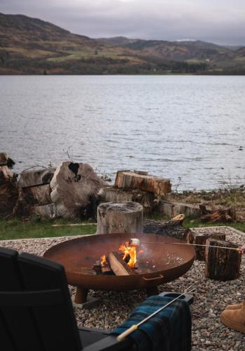 a fire pit next to a body of water at Shoreland Lodges - Holly Lodge in Fort Augustus
