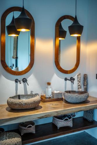 two sinks on a wooden counter with two mirrors at Hatiku Di Bali - Ubud in Tegalalang