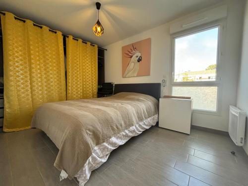 - une chambre avec un lit doté de rideaux jaunes et d'une fenêtre dans l'établissement Charmant T2 avec piscine, à La Londe-les-Maures