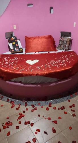 - un lit avec des draps rouges et des roses au sol dans l'établissement Parejas, à La Orilla