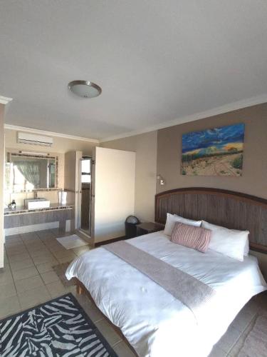 a bedroom with a large white bed and a bathroom at Goba Lodge in Gobabis