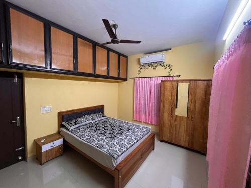 Schlafzimmer mit einem Bett und einem Deckenventilator in der Unterkunft Manasam Homes in Kunnamangalam