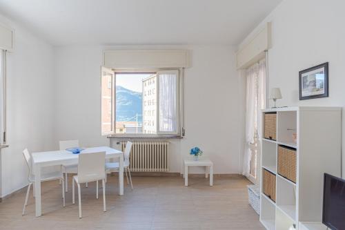 a white dining room with a table and chairs at GuestHost - La Perla in Lierna