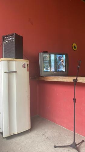 einen TV auf einem Regal neben einem Kühlschrank in der Unterkunft Espaço Rústico in Macaé