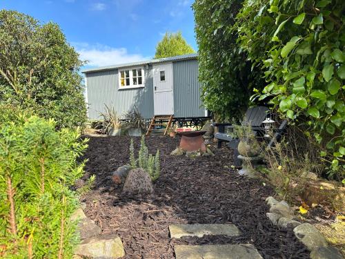 einen Garten mit einem kleinen Schuppen im Hintergrund in der Unterkunft Miners Hut in St Austell