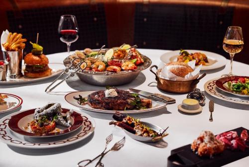 una mesa con platos de comida y copas de vino en Bowie House, Auberge Collection, en Fort Worth