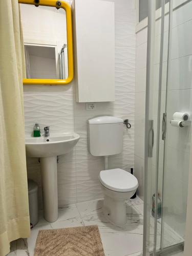 uma casa de banho com um WC, um lavatório e um espelho. em Camere in appartamento condiviso, vista sulla città em Udine