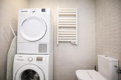 een wasmachine en droger in een badkamer met een toilet bij Casa con bonitas vistas en Montjuic Girona in Girona