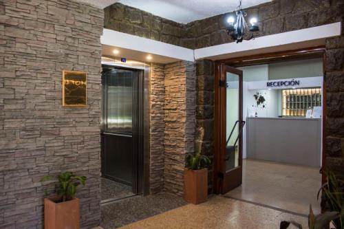 um lobby com uma parede de tijolos e uma porta em Hotel El Libertador em La Falda