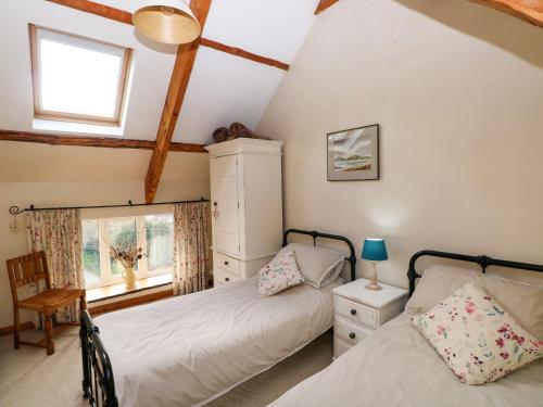 1 dormitorio con 2 camas y ventana en 1 Mill Farm Cottages, en Narberth