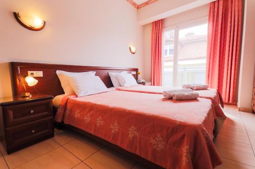 a bedroom with two beds with red sheets and a window at Kymata in Paralia Katerinis