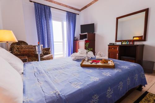 a bedroom with a blue bed with a tray of food on it at Kymata in Paralia Katerinis