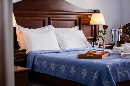 a bed with a blue comforter and a table with wine glasses at Kymata in Paralia Katerinis