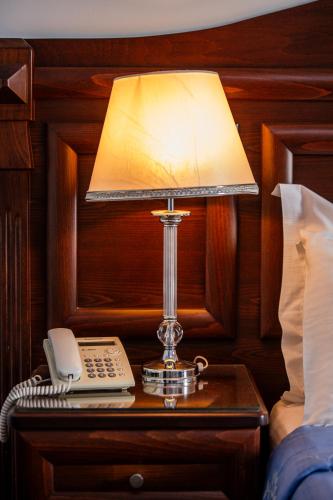 a lamp on a table with a phone on a bedside table at Kymata in Paralia Katerinis