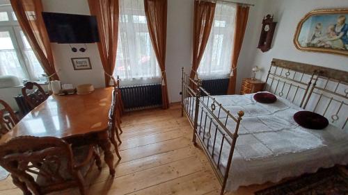 sypialnia ze stołem i łóżkiem oraz drewnianą podłogą w obiekcie Zlatá léta - apartmánový dům Jáchymov w mieście Jáchymov