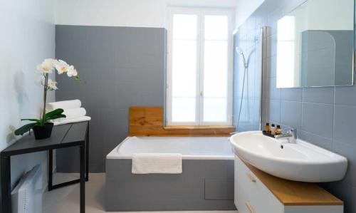 a bathroom with a white tub and a sink at Appartement Porte de Versailles in Malakoff