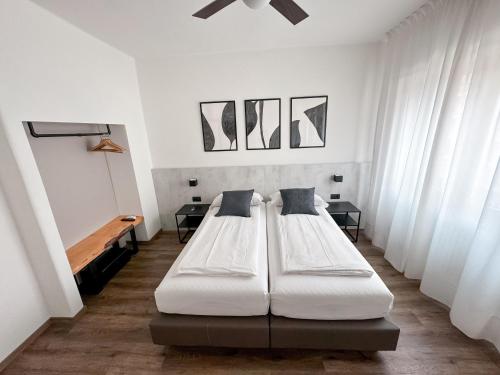 2 letti in una camera con pareti e finestre bianche di Villa Paola B&B a Torbole