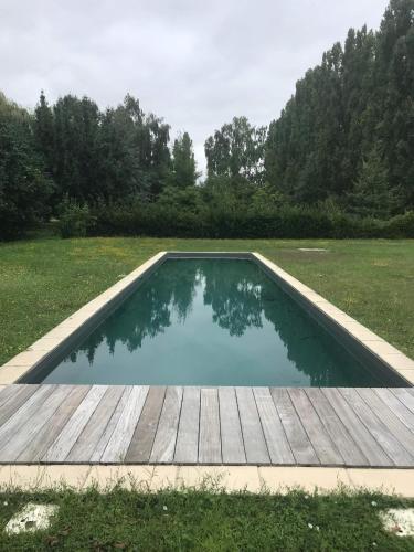 - une piscine dans un champ avec une terrasse en bois dans l'établissement Le gîte du Bois de Sanzay, à Saint-Martin-de-Sanzay