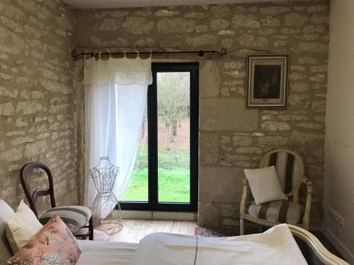 a bedroom with a bed and a window and chairs at Le gîte du Bois de Sanzay in Saint-Martin-de-Sanzay