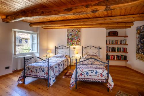 two beds in a bedroom with a wooden ceiling at Dal Picasass House in Madonna del Sasso