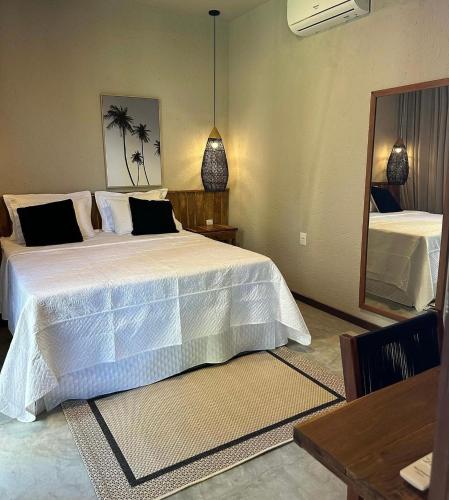 a bedroom with a large white bed and a mirror at Casa Flor São Miguel dos milagres 11 in Barra do Camaragibe