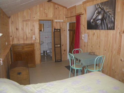 een slaapkamer met een tafel en een paardenfoto aan de muur bij Chambre triple du grand sapin 