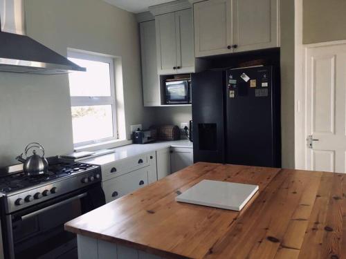 a kitchen with a wooden table and a black refrigerator at Rusenvrede Self Catering in Cape St Francis