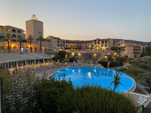 un complexe avec une grande piscine au crépuscule dans l'établissement Appartement village Cap-Esterel - Agay - Saint-Raphaël, à Agay