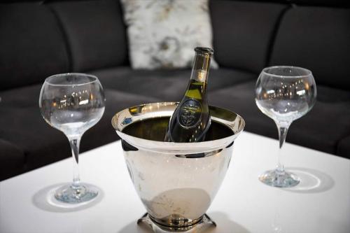 a bottle of wine in a bucket on a table with two wine glasses at Villa HS in Mostar
