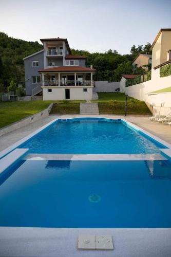 a large blue swimming pool in front of a house at Villa HS in Mostar