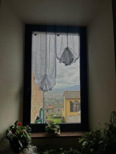 a window with a white curtain and a view at "FUERTE " Affittacamere in Montevettolini