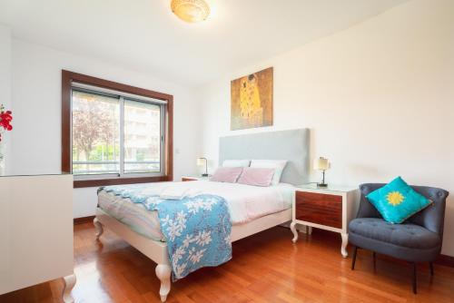 a bedroom with a bed and a blue chair at Apartment Qian Rio Douro 2BR Free Parking in Porto