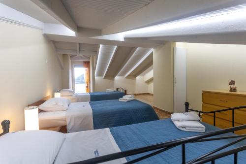 a room with three beds with blue and white sheets at RENT HOUSE BEACH MIRTOFITO 8 km FROM PERAMOS in Elaiokhórion