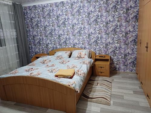 um quarto com uma cama com papel de parede floral em Rent an apartment em Bălţi