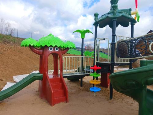 a playground with a slide in the sand at Motylowe Wzgórze Apartamenty Zawóz in Zawóz