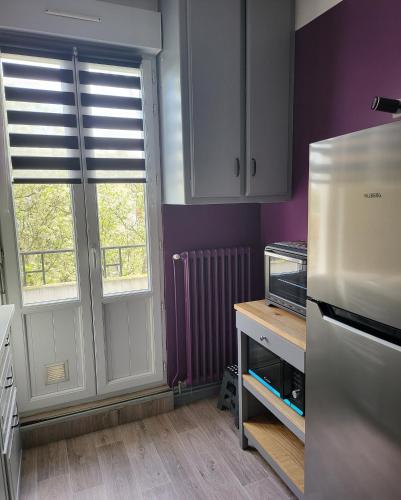 - une cuisine avec des murs et des fenêtres violets et un réfrigérateur dans l'établissement Chez lolo Cosy et chaleureux, à Vichy