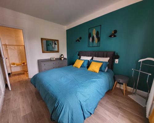 - une chambre avec un grand lit bleu et des oreillers jaunes dans l'établissement Chez lolo Cosy et chaleureux, à Vichy