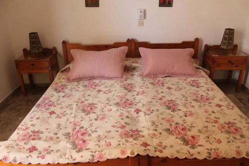 a bed with two pink pillows and a floral blanket at Cozy double apartment near the sea in Tolo