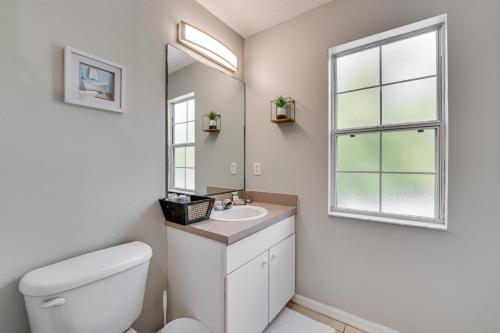 a bathroom with a toilet and a sink and a window at 8 Mi to Disney Villa with Screened Pool and Lanai in Kissimmee