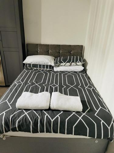 a black and white bed with white pillows on it at Bustling Western Apartment in London