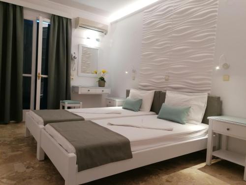 a white bedroom with a large white bed with pillows at LITO STUDIOS APARTMENTS in Pythagoreio