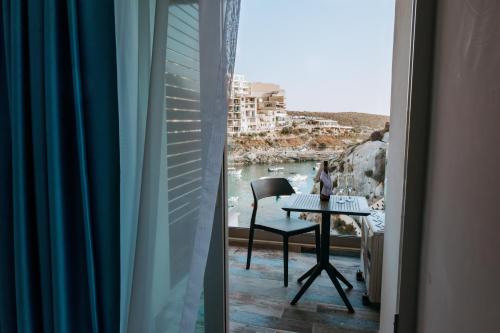 a window with a table and a view of the water at Blu Waters Boutique Hotel in Xlendi