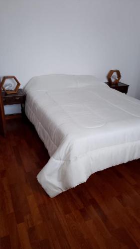 a large white bed sitting on top of a wooden floor at Costa Edison in Mar del Plata